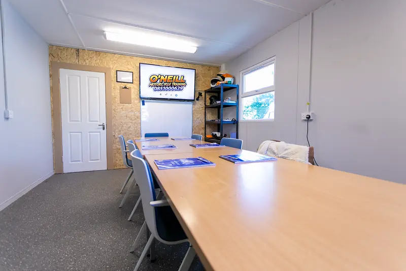 The O'Neill Motorcycle Training classroom with a long table, chairs, handouts and a screen
