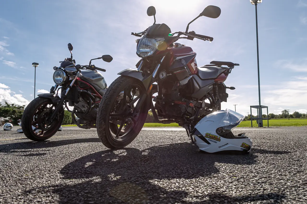 Training motorcycles and an O'Neill helmet on the yard, lit from behind by the sun