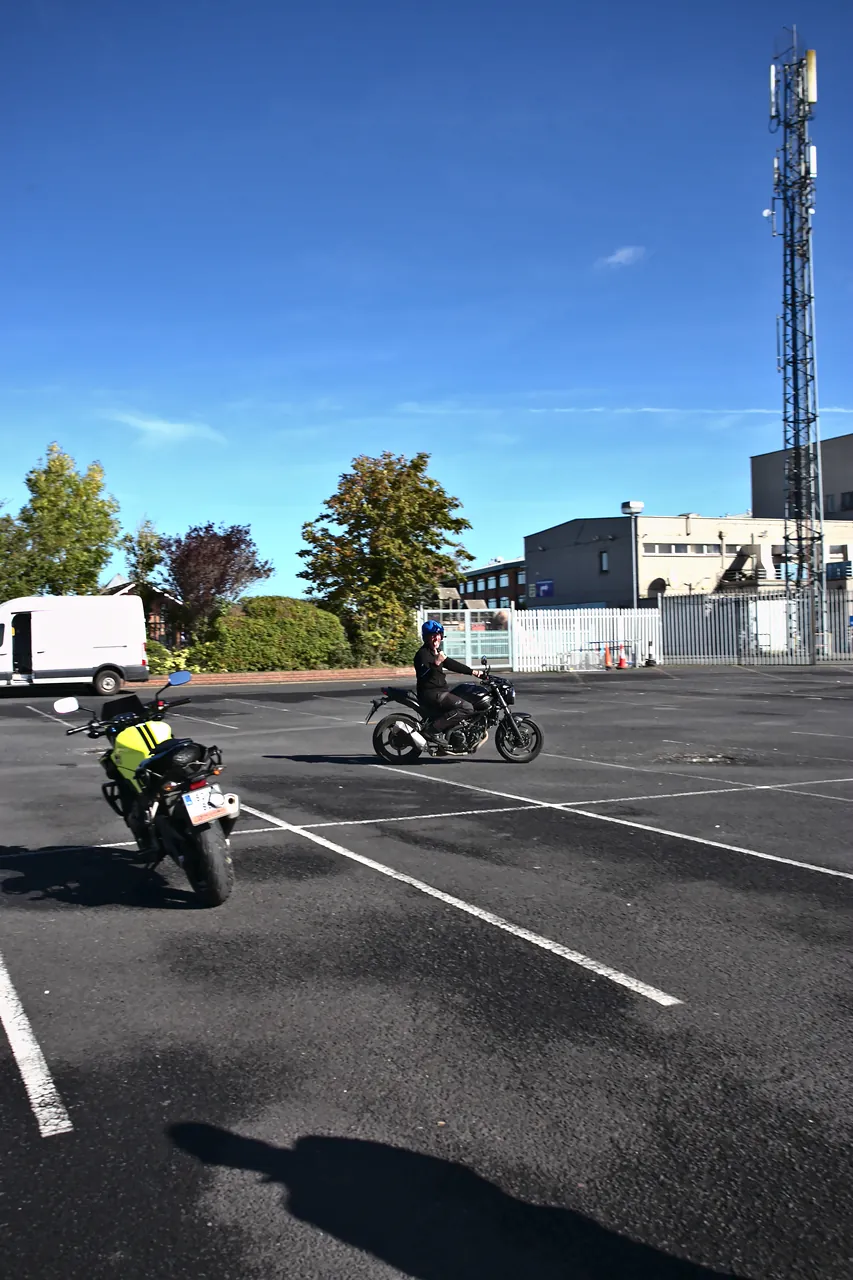 Learner rider in a hi-vis vest on a training motorcycle, with the O'Neill van behind