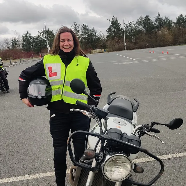 Rider smiling beside a training bike on the manoeuvres pad